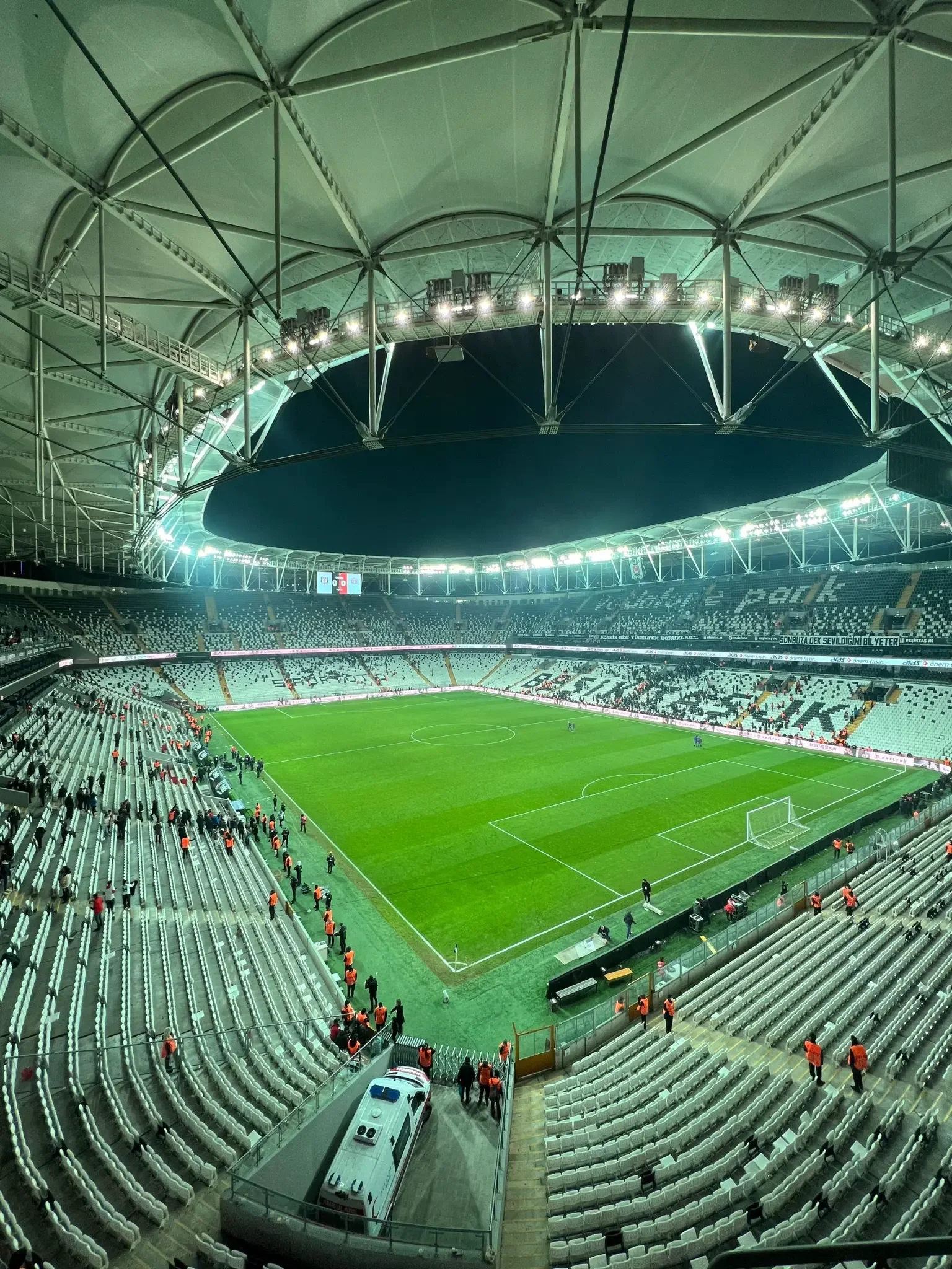 Interior de estádio iluminado com campo e arquibancadas